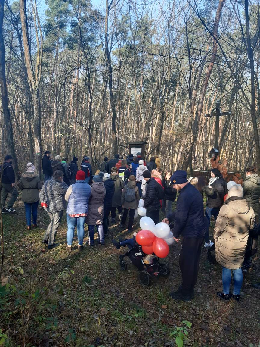 Spacer w lesie, jedna z osób trzyma pęk biało-czerwonych balonów