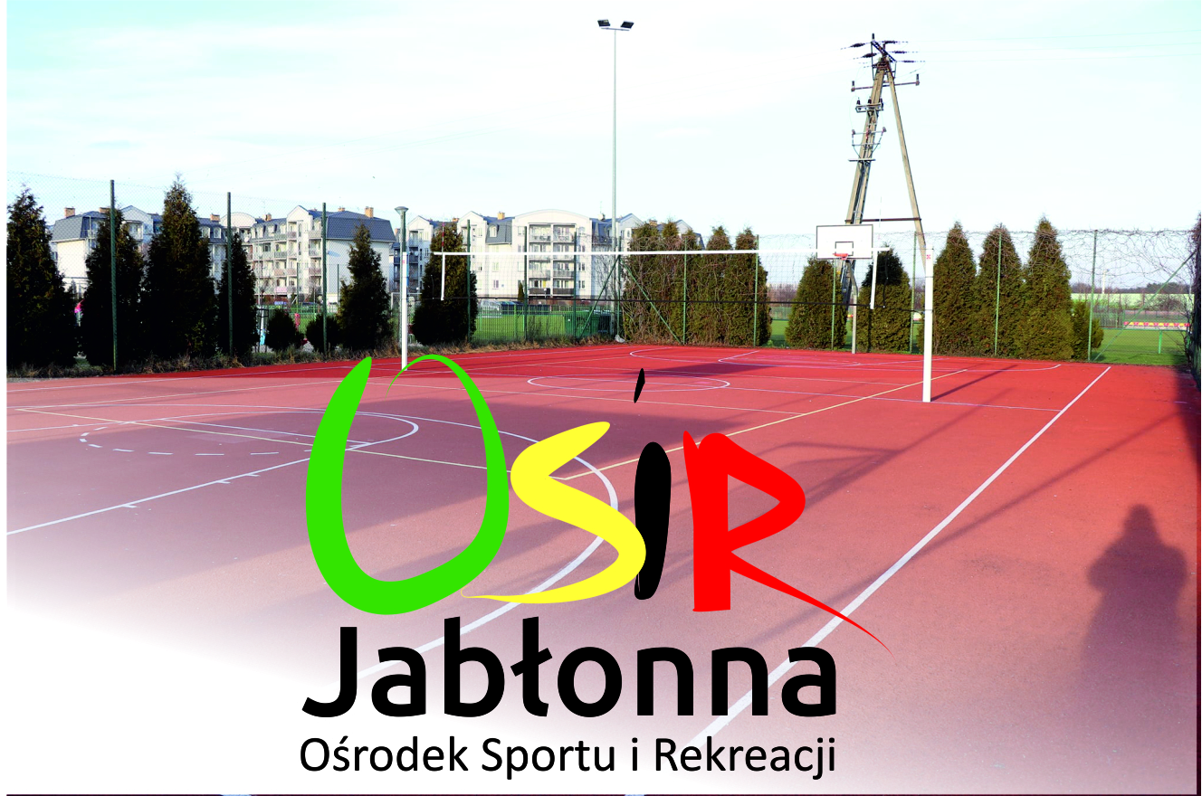 Na pierwszym planie widać nawierzchnię boiska oraz logo OSiR Jabłonna i napis: Ośrodek Sportu i Rekreacji. W oddali widać bloki mieszkalne.